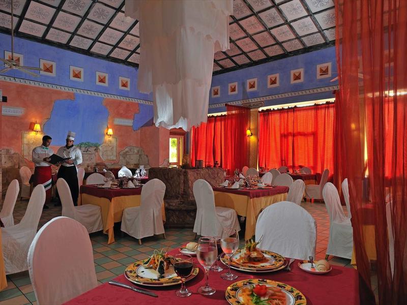 Sala ristorante elegante con tavoli apparecchiati, tovaglie rosse e tende rosse luminose.