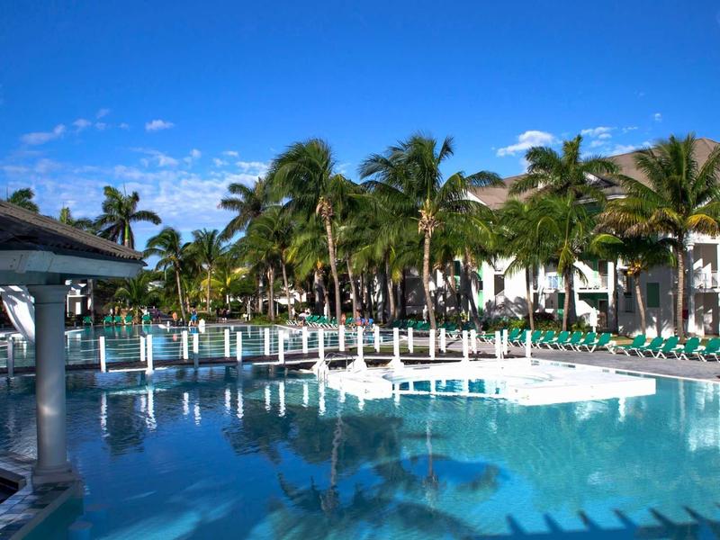 Piscina dell'hotel con palme, lettini e cielo azzurro.