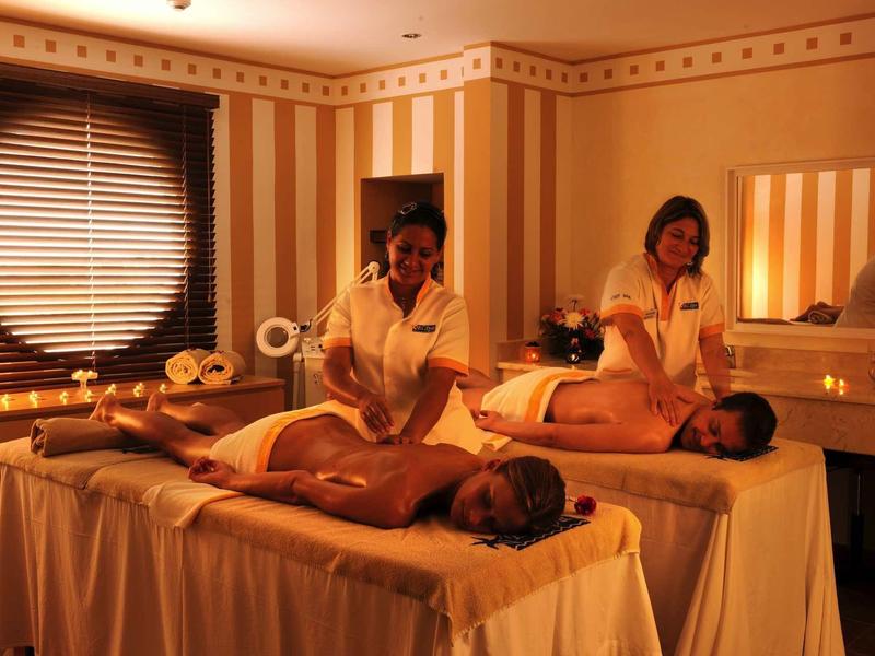 Accogliente stanza spa con due donne che si rilassano su lettini da massaggio ricevendo trattamenti.