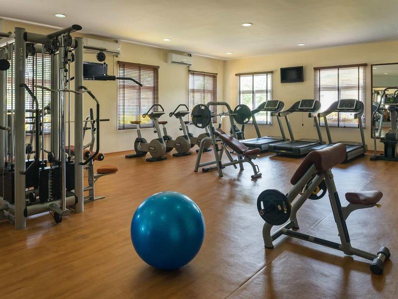 Een moderne fitnessruimte met apparatuur, halters en een blauwe fitnessbal op een houten vloer.