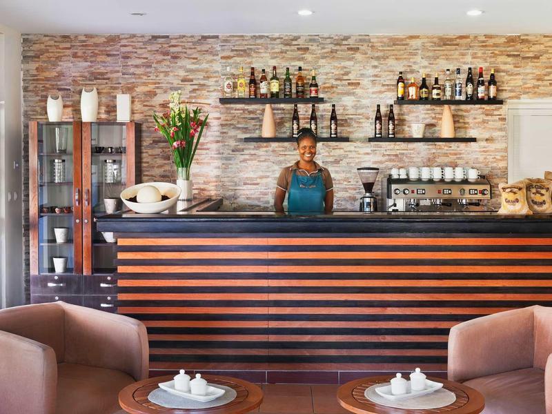 Moderne hotellobby met comfortabele fauteuils en een bar tegen een vlakke stenen muur.