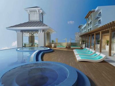 Zona piscina moderna dell'hotel con jacuzzi, lettini e vista mare sotto un cielo limpido.