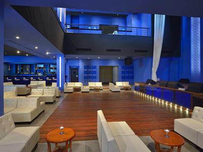 Moderní hotelová lounge s bílými pohovkami a modrým osvětlením.