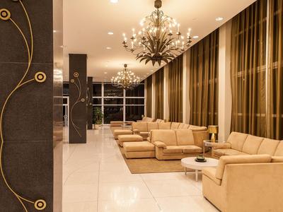 Hall d'hôtel élégant avec canapés beiges, lustres et grandes fenêtres avec rideaux.