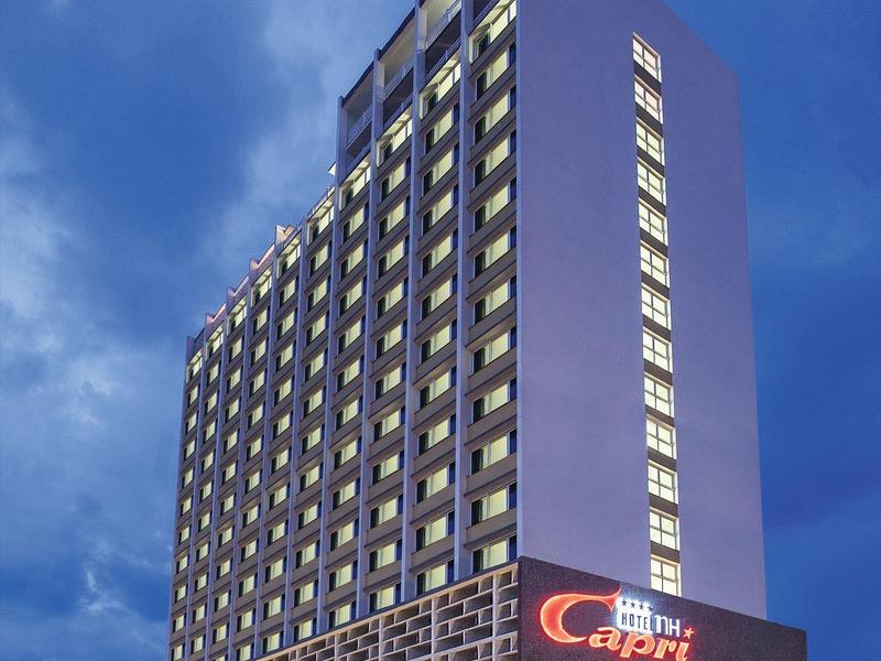 Grand bâtiment d'hôtel illuminé au crépuscule avec enseigne 'Hotel Capri'.