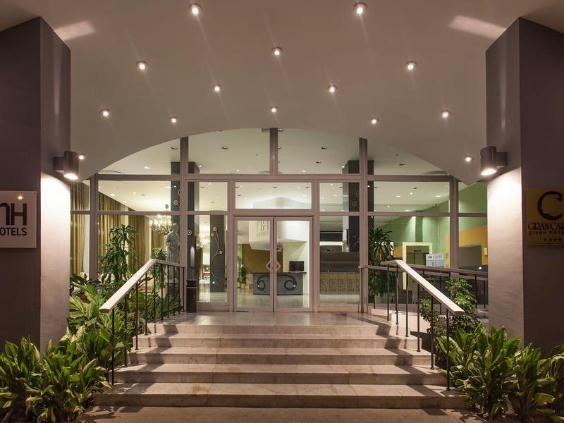 Entrée d'hôtel avec escaliers éclairés et portes coulissantes en verre la nuit