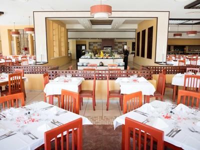 Restaurant mit weißen Tischdecken, roten Holzstühlen und Buffetbereich im Hintergrund.