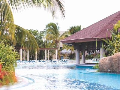 Área de piscina con plantas tropicales y pabellón cubierto en complejo hotelero