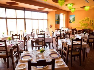 Restaurant mit Holzmöbeln und weißen Tischdecken, große Fenster sorgen für viel Tageslicht.