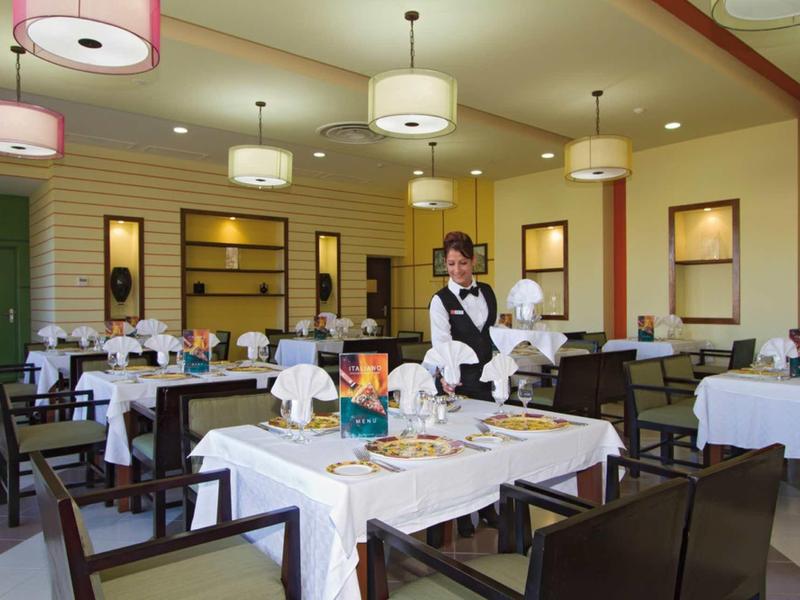 Elegantes Restaurant mit weiß gedeckten Tischen, dunklen Stühlen und modernem Lampenschirm.