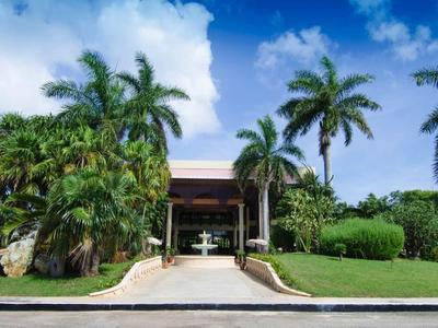 Hôtel avec des palmiers et un aménagement paysager verdoyant sous un ciel bleu