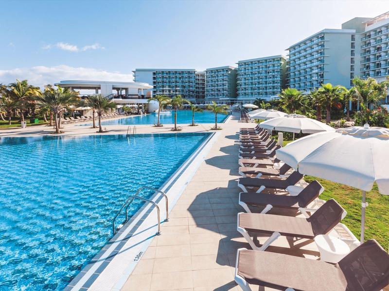 Vista di una piscina all'aperto con lettini e ombrelloni in un hotel moderno.