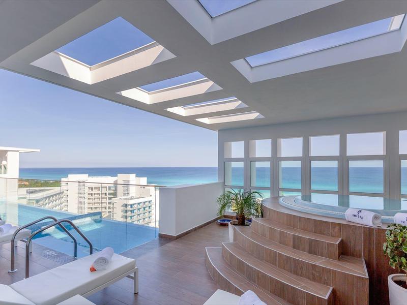 Terrazza dell'hotel con piscina, vista mare e arredamento in legno sotto un tetto aperto.