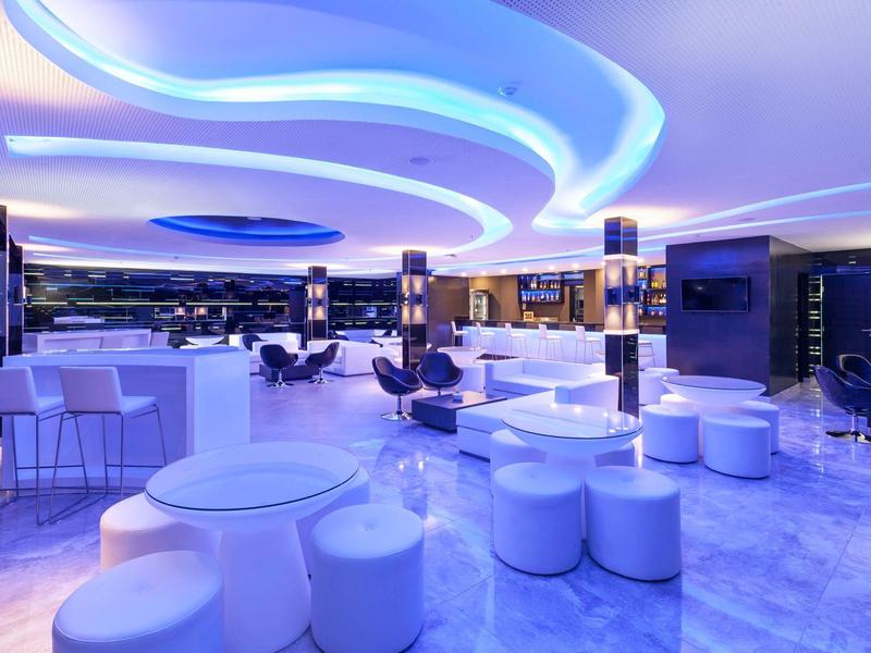 Locale moderno e luminoso con sedute bianche, bar e illuminazione blu rilassante.