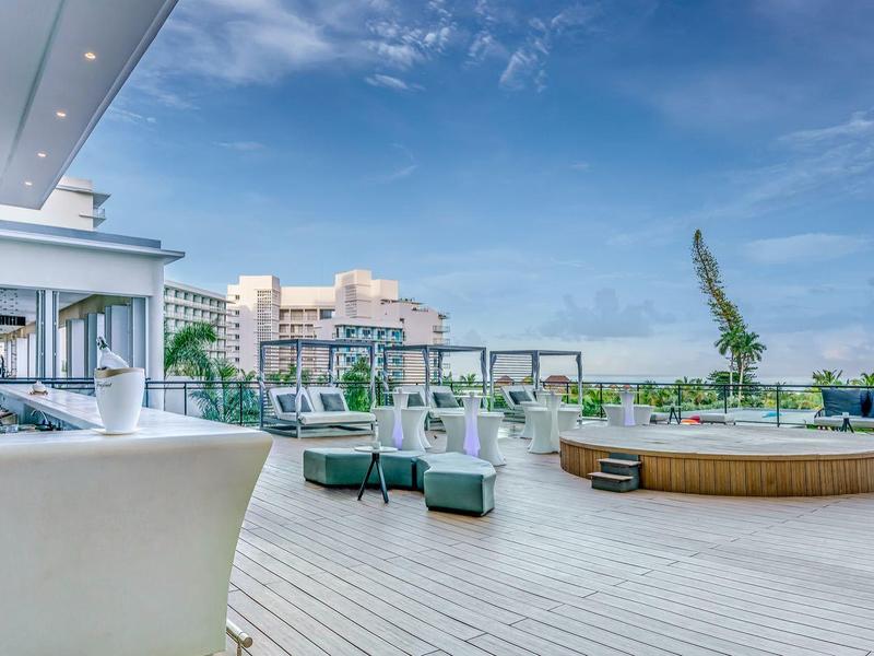 Terrazza di hotel moderna con sedute bianche e vista libera sotto un cielo azzurro.