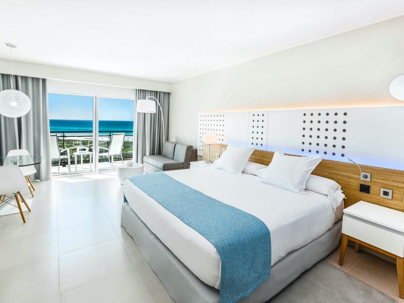 Camera d'hotel moderna con letto matrimoniale, balcone e vista mare.