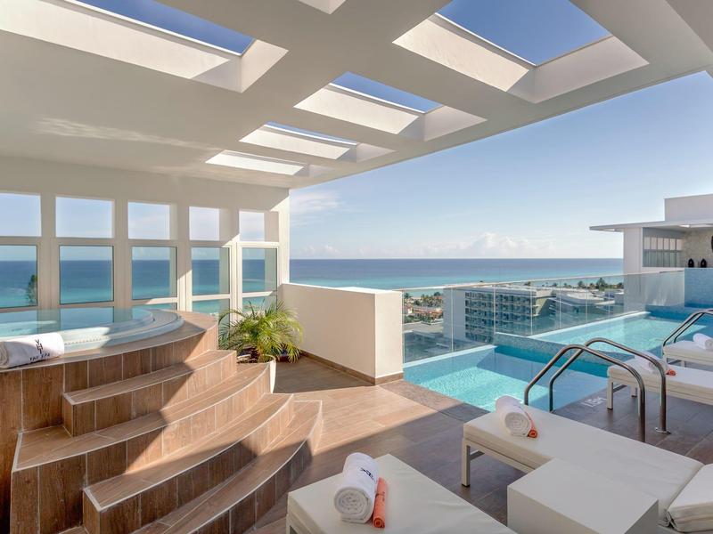 Terrazza con vasca idromassaggio, piscina e vista mare sotto il sole.