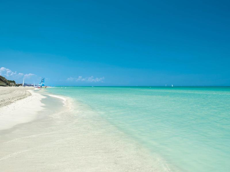 Spiaggia di sabbia bianca con acqua turchese limpida e cielo azzurro