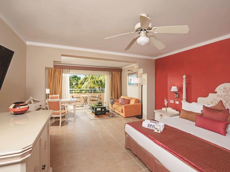 Camera d'hotel accogliente con letto matrimoniale e balcone con vista su piante verdi.