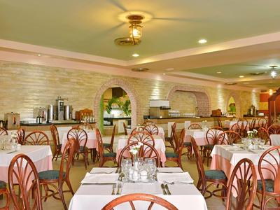 Sala da pranzo luminosa con molti tavoli e sedie in un hotel.