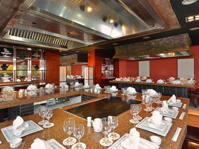 Ristorante moderno con tavoli in legno apparecchiati con piatti bianchi e bicchieri, pareti rosse.