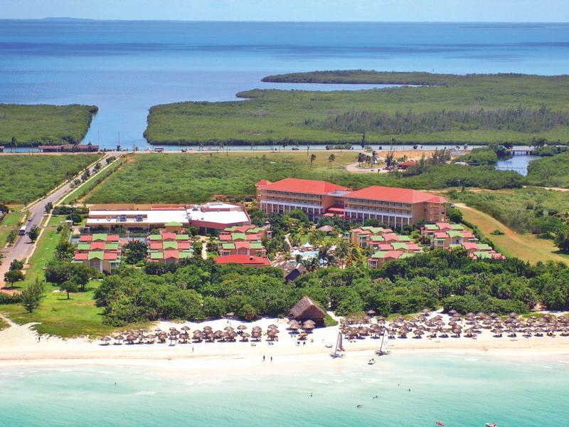 Grande resort alberghiero con piscina e spiaggia sulla costa in un ambiente tropicale.
