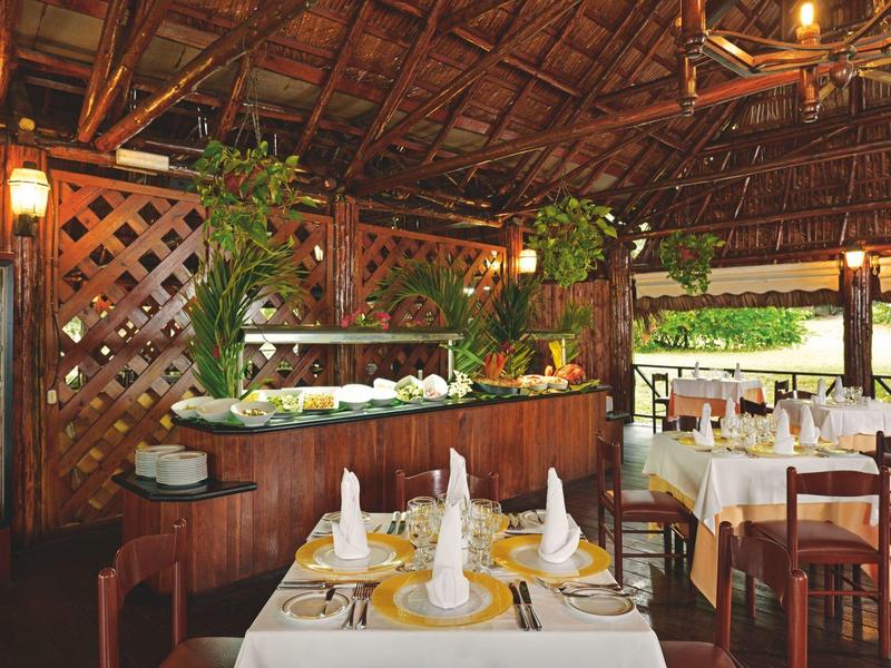 Ristorante accogliente con tetto in legno e tavoli decorati in un ambiente tropicale.