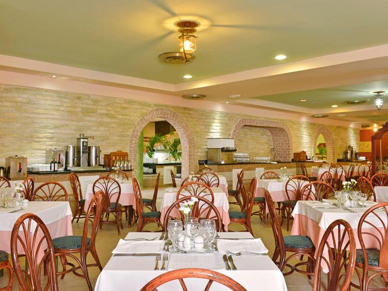 Sala da pranzo luminosa con molti tavoli e sedie in un hotel.