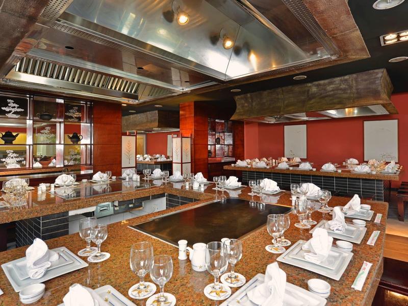 Ristorante moderno con tavoli in legno apparecchiati con piatti bianchi e bicchieri, pareti rosse.