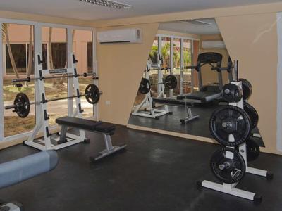 Gimnasio moderno con pesas, banco de entrenamiento y grandes espejos en un hotel.