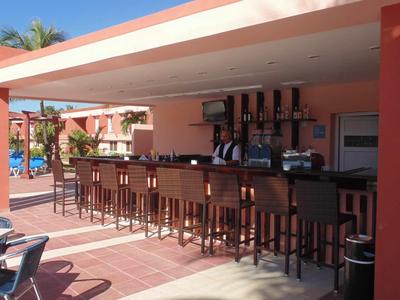 Bar all'aperto con sgabelli sotto tetto in giardino di hotel soleggiato con piscina