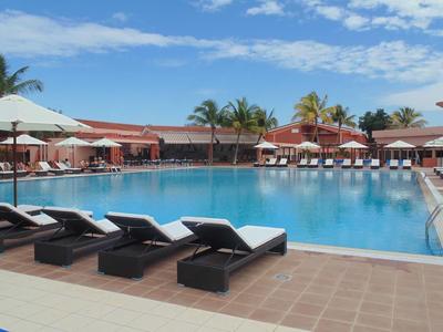 Gran piscina al aire libre con tumbonas y sombrillas bajo un cielo azul