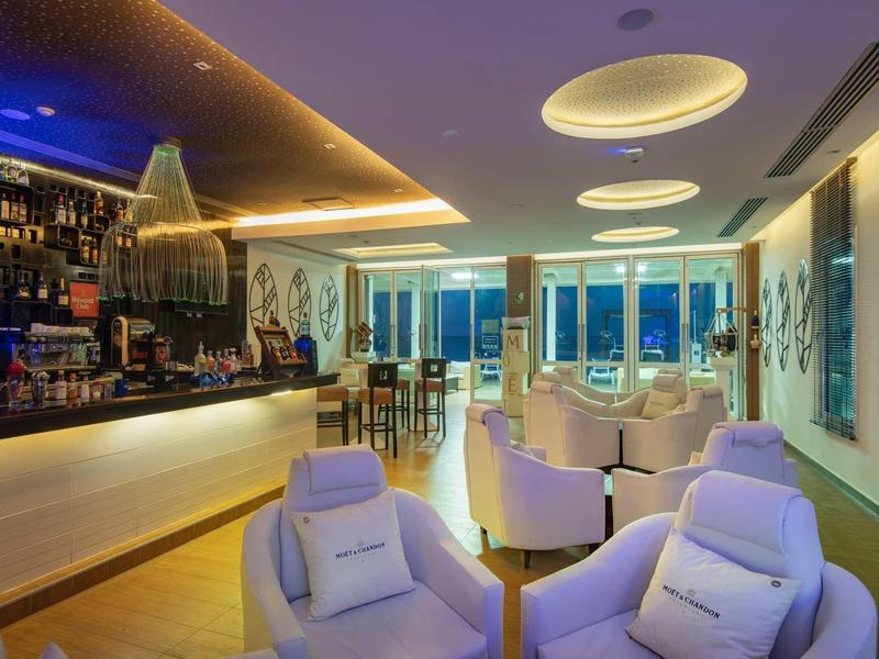 Bar dell'hotel moderno con aree salotto luminose e vista panoramica sotto luce calda.