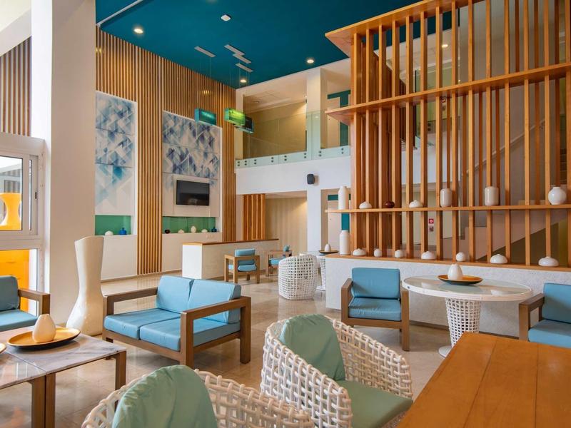 Area lounge moderna in hotel con poltrone blu, pareti in legno ed elementi decorativi.