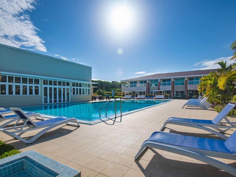 Piscina moderna dell'hotel con lettini prendisole e cielo azzurro terso durante il giorno