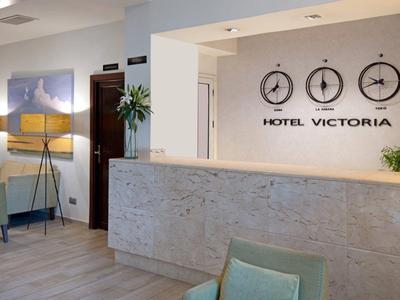 Nowoczesna recepcja hotelowa z kamiennym kontuarem, zegarami ściennymi i stylowym wystrojem.