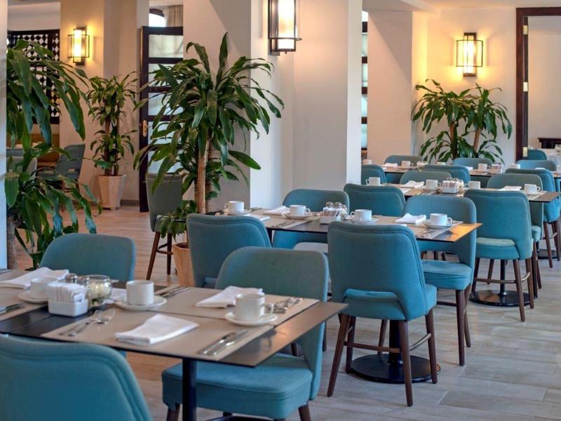 Moderne ontbijtruimte met blauwe stoelen en houten tafels in een hotel.