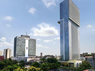 Two modern high-rise buildings in a cityscape with blue sky and green trees.