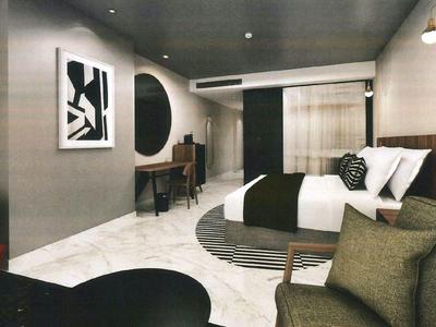 Modern hotel room with double bed, seating area, and stylish wall decor.