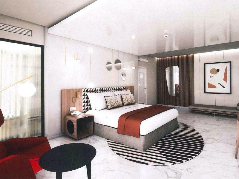 Modern hotel room with bed, seating area, and abstract wall art.