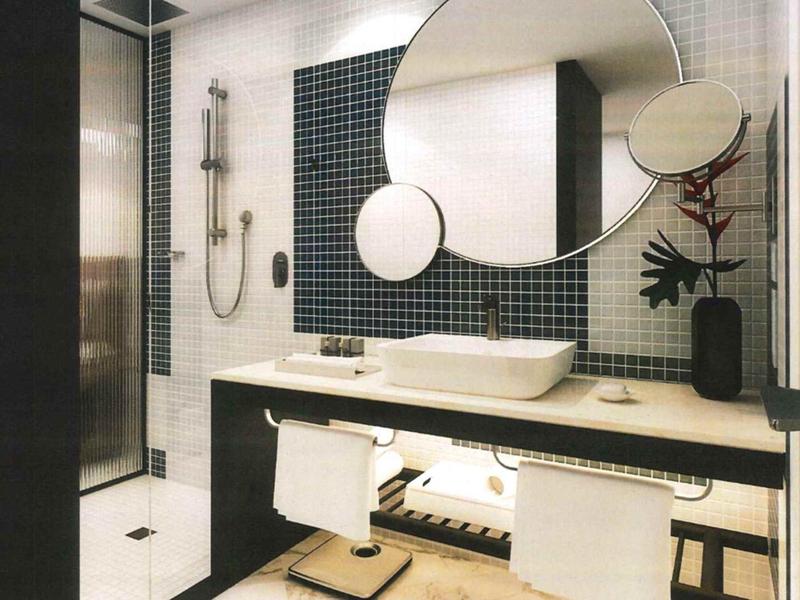 Modern bathroom with round mirror, double sinks, and towels in a hotel.