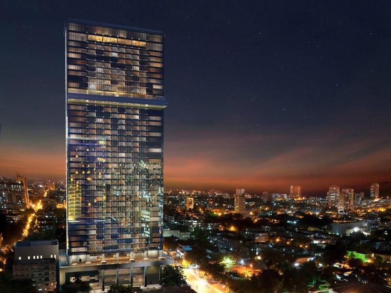 High-rise building lit at night with city lights and streets in the foreground.