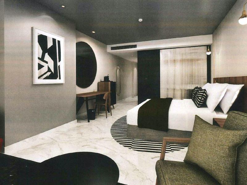 Modern hotel room with double bed, seating area, and stylish wall decor.