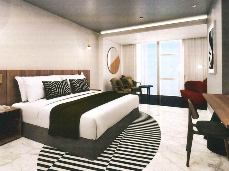 Modern hotel room with large double bed, seating area, and balcony access.