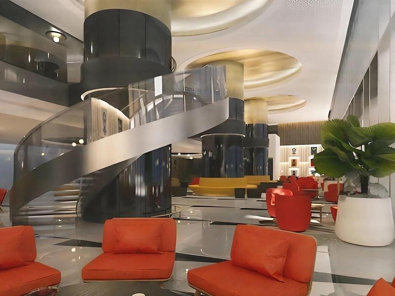 Modern hotel lobby with red armchairs and a spiral staircase.