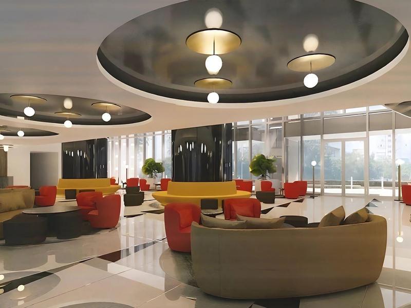 A modern hotel lobby area with round sofas, large mirrors, and bright ceiling lights.