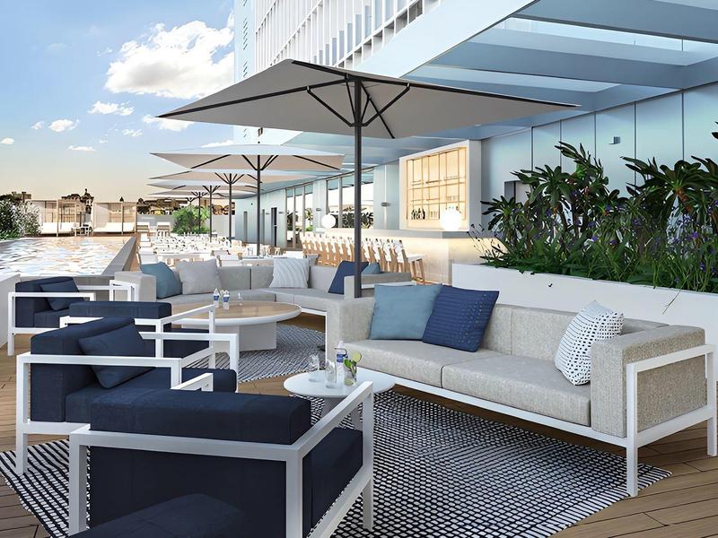 Modern hotel terrace with stylish seating, umbrellas, and city views.