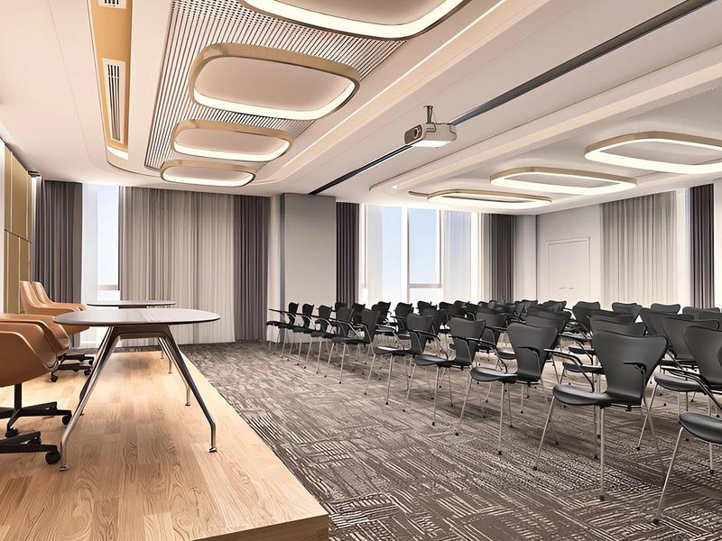 Modern conference room with rows of chairs and speaker podium in neutral tones.