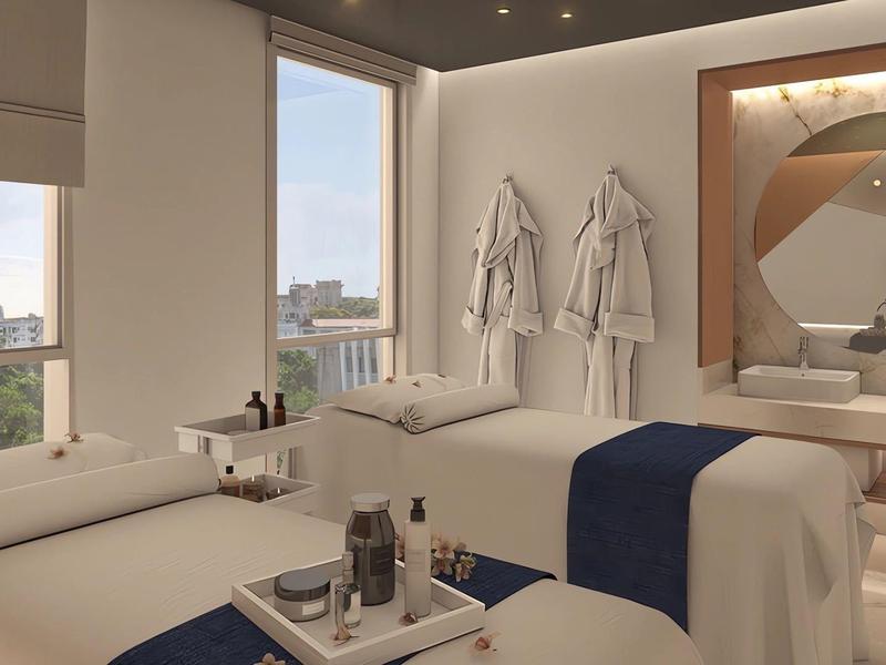 Bright modern spa room with two massage tables, towels, and city view.