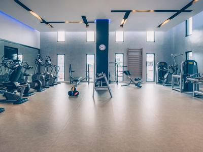 Una palestra moderna e spaziosa con varie attrezzature da allenamento e illuminazione luminosa.